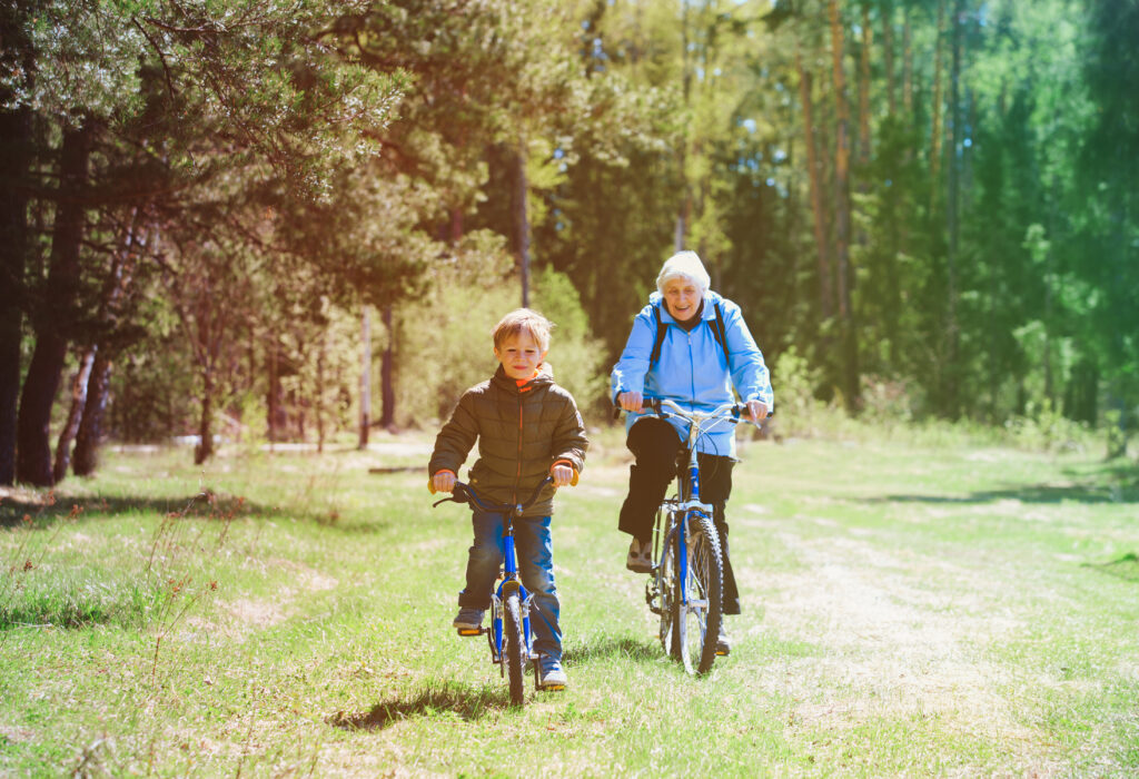 active senior grandmother with grandson riding bikes in nature